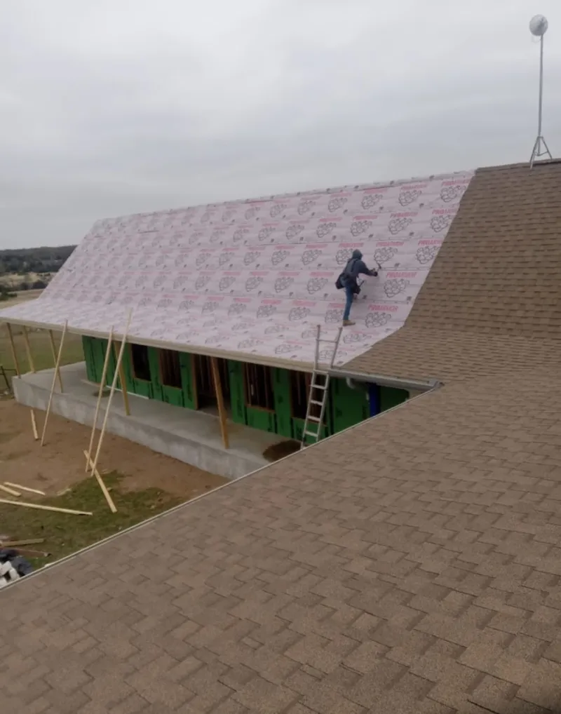Worker preparing underlayment for a metal roof installation in Chanhassen